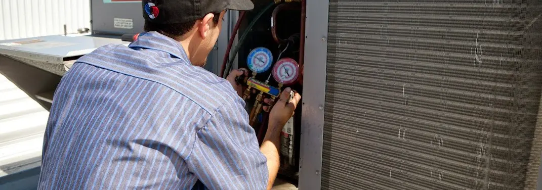 HVAC technician servicing a condenser unit in Burlington